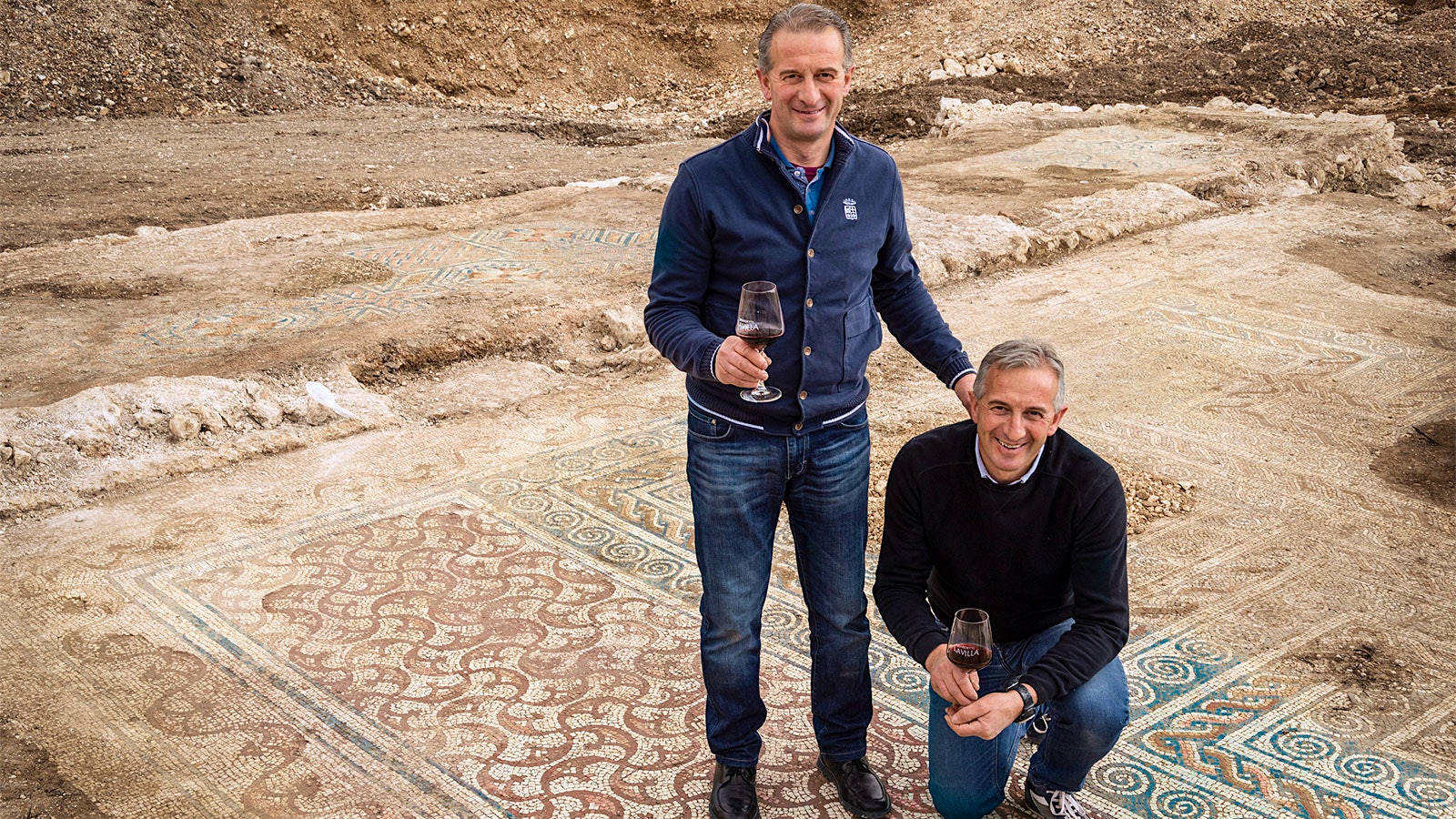 Brothers Matteo (standing) and Simone (kneeling) Benedetti atop one of the floor mosaics uncovered at the ancient Roman villa on their winery property